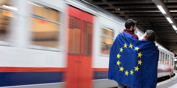 Train and people on platform, holding an EU flag